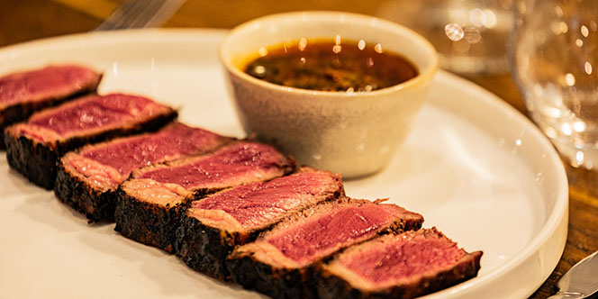 ASA Restaurant Montpellier : tranches de viande grillée, servies rosées avec une sauce dans une assiette blanche.
