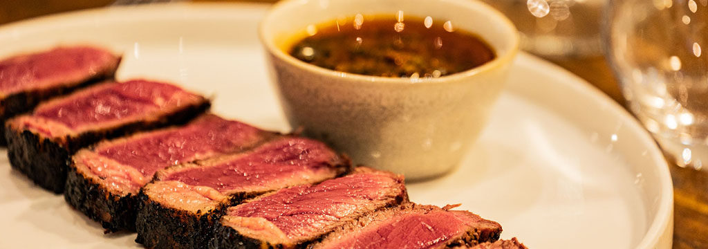 ASA Restaurant Montpellier : tranches de viande grillée, servies rosées avec une sauce dans une assiette blanche.